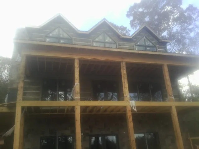 Dormers and porch framing on a large log home under construction — Roof Coating work by our crew in Wayne